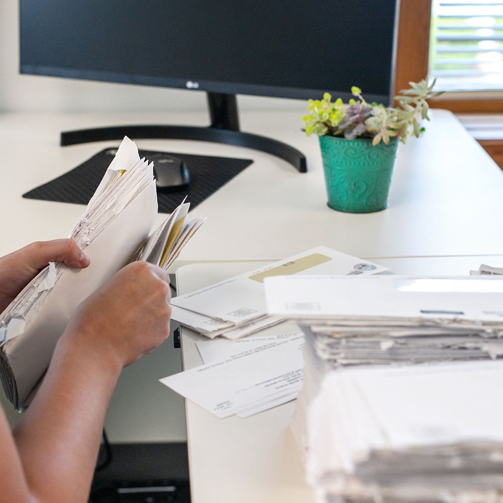 A person sorts mail at a workspace