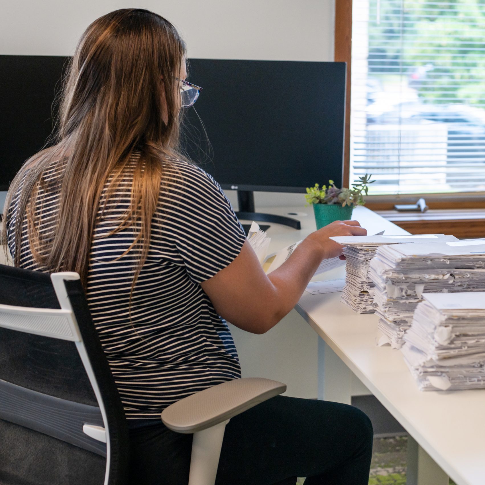 A woman sorts mail at a desk