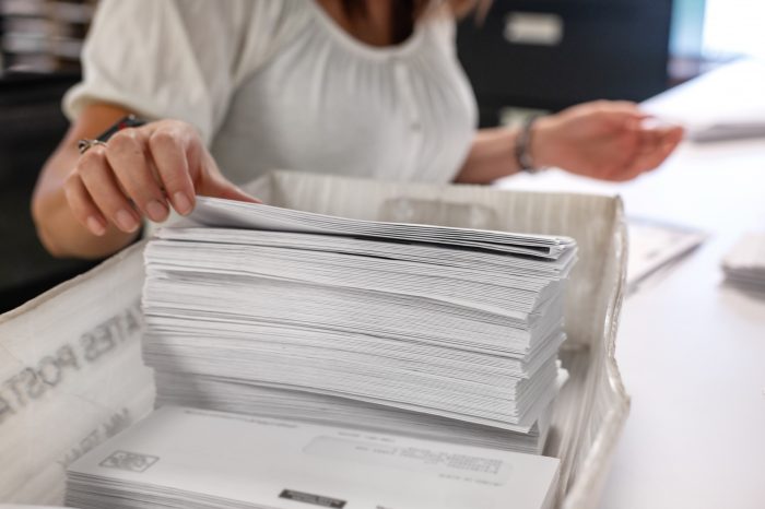 A hand grabs mail from a basket