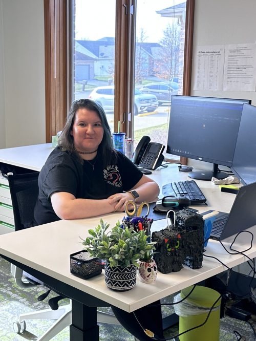 A woman sits at a desk with some decor and a computer