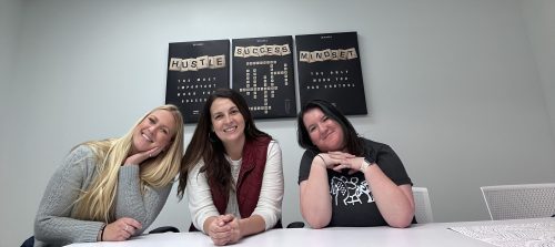 Three women smiling across a table