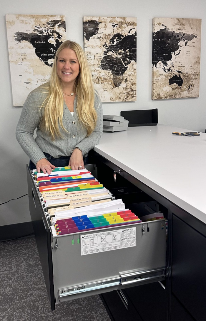 A woman sorts through documents in a large filing cabinet