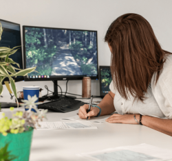 Woman at a desk writing on a piece of paper.